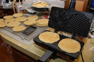 Kitchen counter with a pizzelle maker and fresh-cooked cookies.