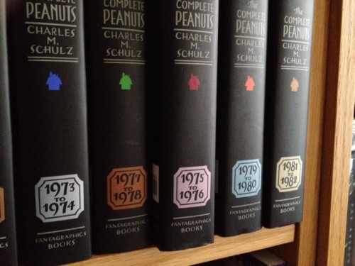 A shelf of "Complete Peanuts" books, with one book out of chronological sequence. 