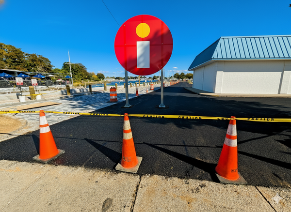 A construction site showing a nearly-complete retail property. Traffic cones and CAUTION tape across the foreground.